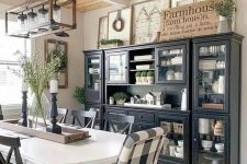 a chic modern farmhouse dining space with black storage units, a white vintage table and mismatching chairs plus a jar chandelier