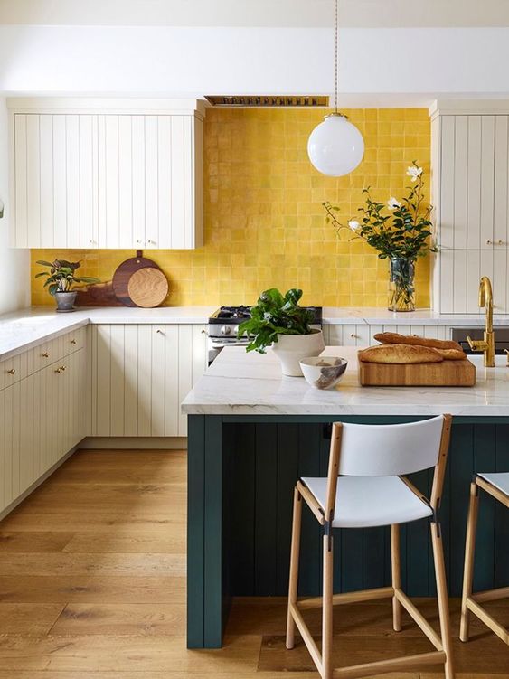 a chic vintage-inspired kitchen with white beadboard cabinets, white stone countertops, a sunny yellow tile backsplash and a hunter green kitchen island