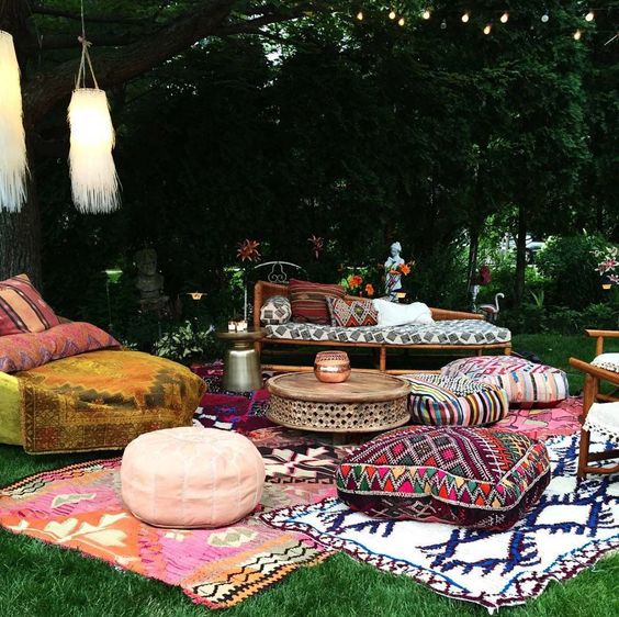 a colorful boho patio with ottomans, cushions, pillows, rugs, rattan furniture and long fringe lamps
