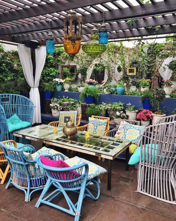 a colorful boho patio with rattan chairs in various colors, colorful pillows, bright glass lanterns and a simple table