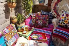 a colorful boho patio with wicker furniture, printed and bright textiles, potted cacti and plants