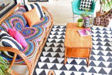 a colorful boho space with rattan furniture, colorful pillows and tetiles, a printed rug and potted plants