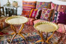 a colorful living room with bright textiles and patterns, gold tables and a macrame hanging