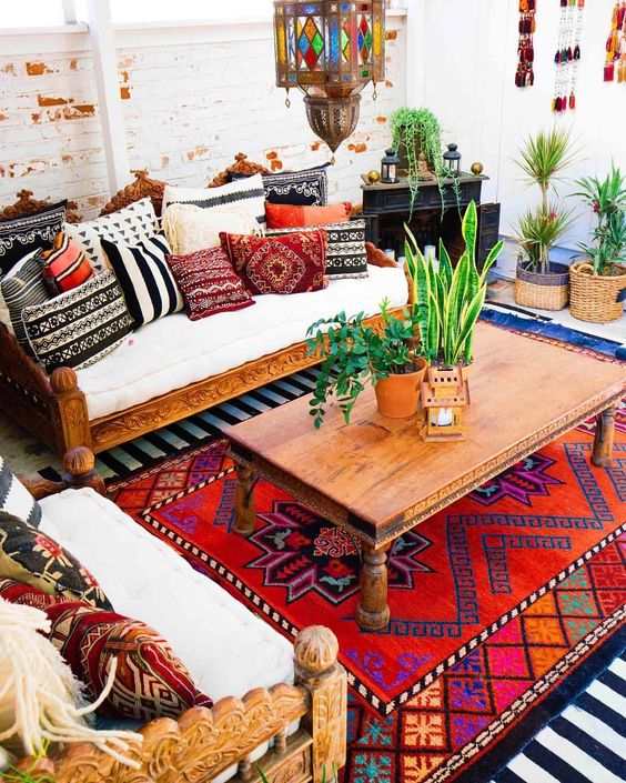 a colorful living room with lots of pillows and rugs, potted plants and mosaic pendant lamps
