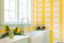 a colorful welcoming kitchen with yellow print wallpaper walls, a mint frame window and mint cabinets for a bold look