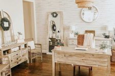 a cozy rustic home office with white beadboard, wooden furniture, a mirror, a pendant lamp and lots of greenery