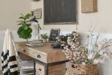 a farmhouse home office with a wooden desk, a chalkboard, baskets on the wall, a basket with flowers on a suitcase