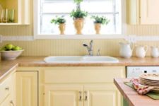 a farmhouse kitchen with light yellow cabinets and a beadboard backsplash, a green kitchen island and a green printed curtain