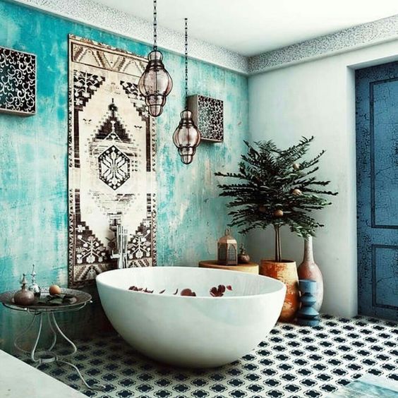 a gorgeous Moroccan bathroom with a turquoise plaster wall, a rug, some lamps and a tiled floor