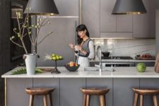 a grey Scandinavian kitchen with sleek lit up cabinets, pendant lamps, white stone countertops and a backsplash