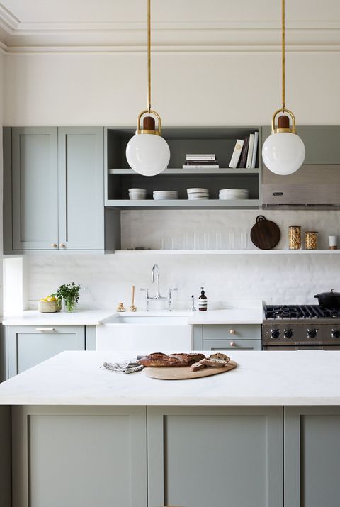 a grey vintage-inspired kitchen with paneled cabinets, white tiles and countertops and pendant lamps