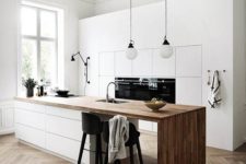a minimalist Nordic kitchen with sleek white cabinets, a sleek white kitchen island with a wooden waterfall countertop and pendant lamps