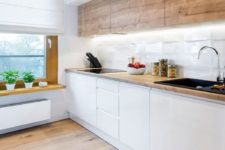 a minimalist Scandi kitchen with wooden upper cabinets, sleek white lower ones, a windowsill shelf and built-in lights