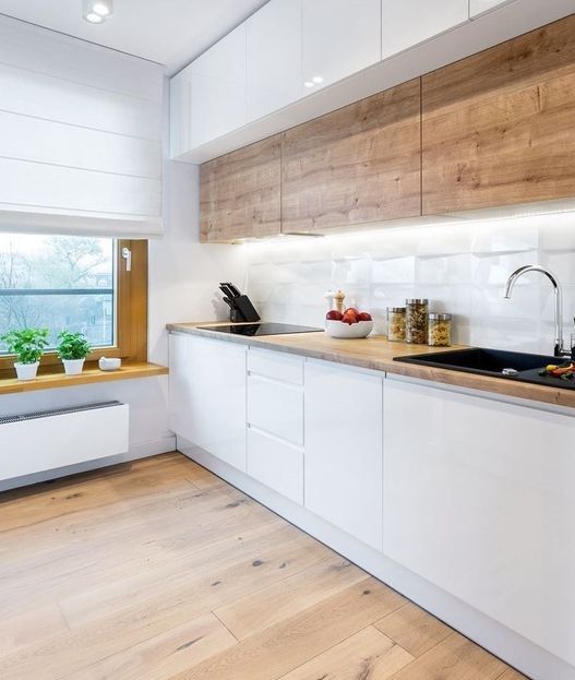 A minimalist Scandi kitchen with wooden upper cabinets, sleek white lower ones, a windowsill shelf and built in lights