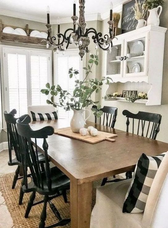 a modern farmhouse dining space done in black and white, with a stained table,a  white wall-mounted shelf and black chairs, a vintage chandelier