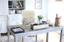 a modern farmhouse home office with a white storage unit, a pale desk, a vintage sphere lamp and faux fur