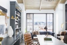 a modern rustic home office with a large graphite grey storage unit, a wooden desk, a leather chair and an antler chandelier