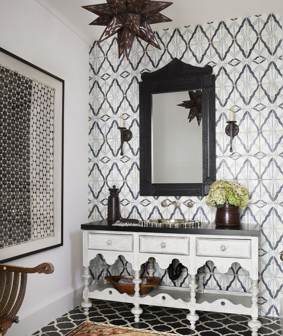 a monochromatic Moroccan bathroom with catchy tiles on the wall and floor and a carved vanity