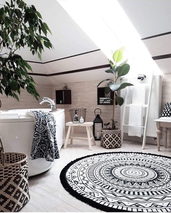 a monochromatic boho bathroom with printed textiles and patterned baskets, plants, a tub and lanterns