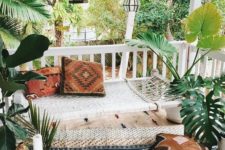 a neutral boho patio with a woven hammock, printed rugs, pillows, candles and lanterns hanging over the space