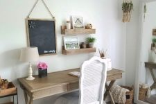 a neutral farmhouse home office with a wooden trestle desk, a white chair, a jute rug and wooden shelves