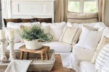 a neutral rustic living room with wooden tables, whitewashed wood elements and white and neutral furniture for a farmhouse feel