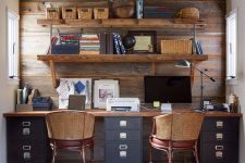 a rustic home office with a salvaged wooden wall, a shared desk, woven chairs and an open shelving unit