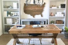 a rustic home office with open storage units, a wooden trestle desk, a printed rug and a state artwork on the wall