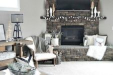 a rustic living room with a stone clad fireplace, a wooden console and a coffee tble plus mini trees