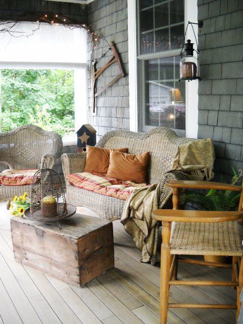 a rustic patio with wicker and wooden furniture, lanterns, a cage candle lantern and striped textiles