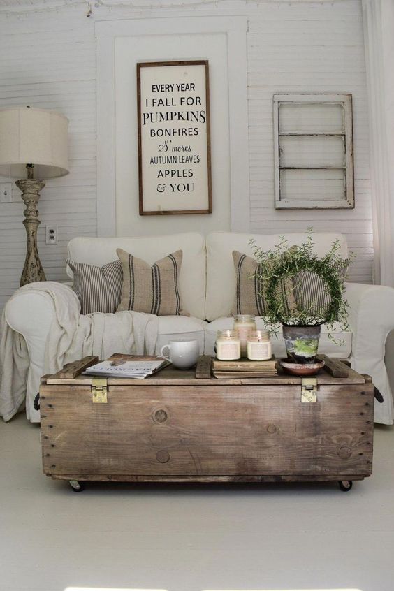 a rustic sitting room with whitewashed shutter walls, neutral furniture and a large stained coffee table