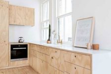 a simple neutral Scandi kitchen with plywood cabinets, white countertops and a wooden floor