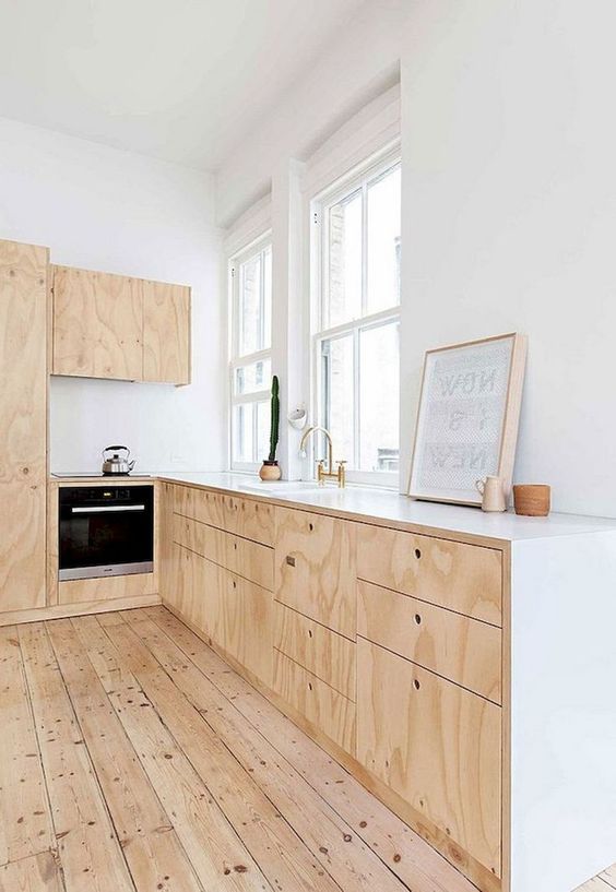a simple neutral Scandi kitchen with plywood cabinets, white countertops and a wooden floor
