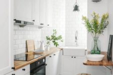 a small Nordic kitchen with white cabinets, black hardware, butcherblock countertops and white tiles plus wood and metal stools