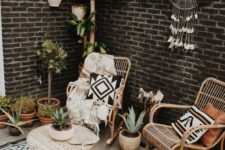 a small and cozy boho patio with rattan furniture, a dream catcher with crystals, a printed rug and pillows and potted plants