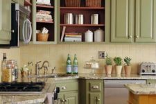 a vintage farmhouse kitchen with soft green cabinets, a light yellow tile backsplash and stone countertops