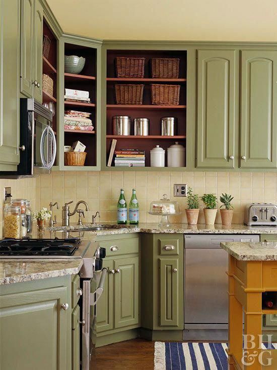 a vintage farmhouse kitchen with soft green cabinets, a light yellow tile backsplash and stone countertops