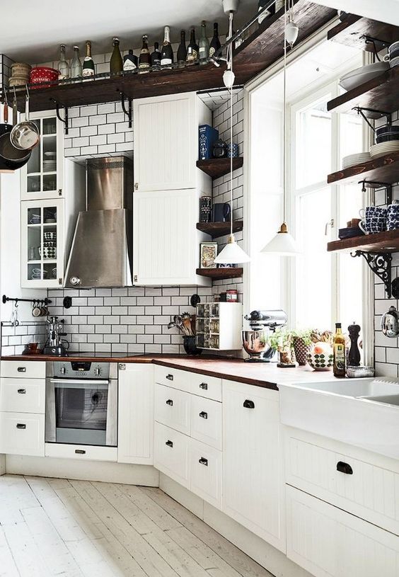 a vintage-inspired Nordic kitchen with a ceiling shelf, white tiles, white vintage cabinets and rich-stained countertops