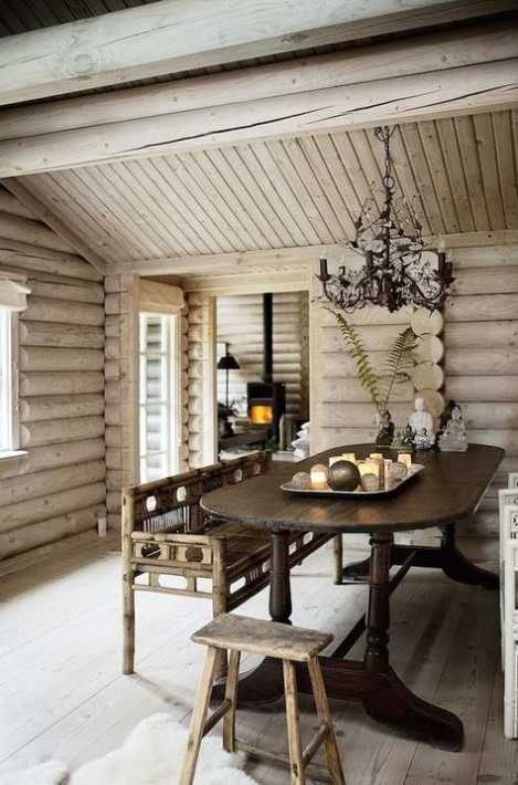 a welcoming rustic dining space clad with whitewashed wood, with vintage furniture, a vintage chandelier and some candles