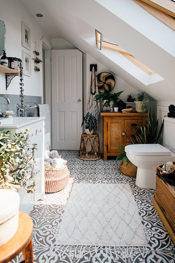 an attic boho bathroom with a wooden cabinet, a rattan side table, a basket and some potted plants