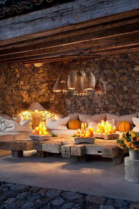 stone walls, a tiled floor, upholstered furniture, wicker lampshades and a low wooden table