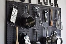 a black pegboard with lots of hangers and hooks is great for hanging pots and pans where you want