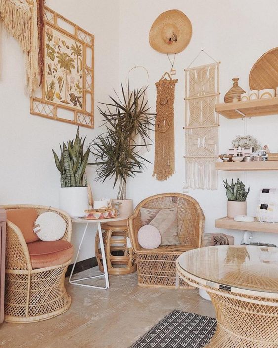 a boho chic home office with rattan furniture, open shelving, macrame hangings and a botanical poster, potted plants and round pillows