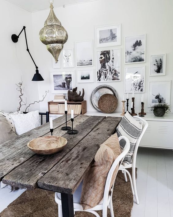 a boho dining space with a rough wooden table, a Moroccan lantern over the space and a gallery wall