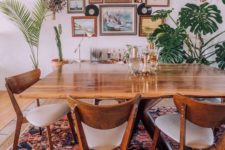 a boho meets mid-century modern space with a cool rug, chic wooden furniture, a gallery wall and potted greenery and palms