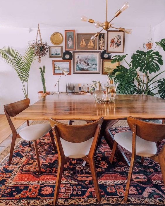 A boho meets mid century modern space with a cool rug, chic wooden furniture, a gallery wall and potted greenery and palms