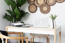 a boho tropical home office with a sleek desk, woven chairs, potted plants, decorative plates on the wall is very airy and cool