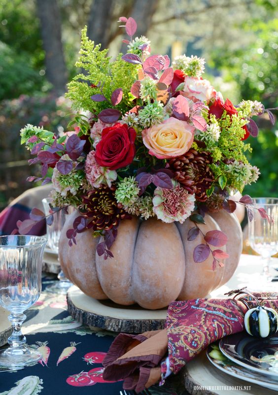 a bold fall centerpiece of a chalky pumpkin, usual and dark foliage, bright blooms is very bright