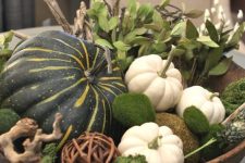 a bowl with moss, vine balls, pumpkins, greenery and driftwood is a nice fall centerpiece with a natural feel