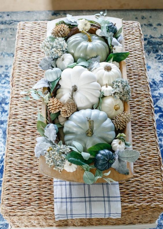 a bread bowl with neutral and pastel pumpkins, blue blooms, bleached pinecones and pale and usual foliage for the fall